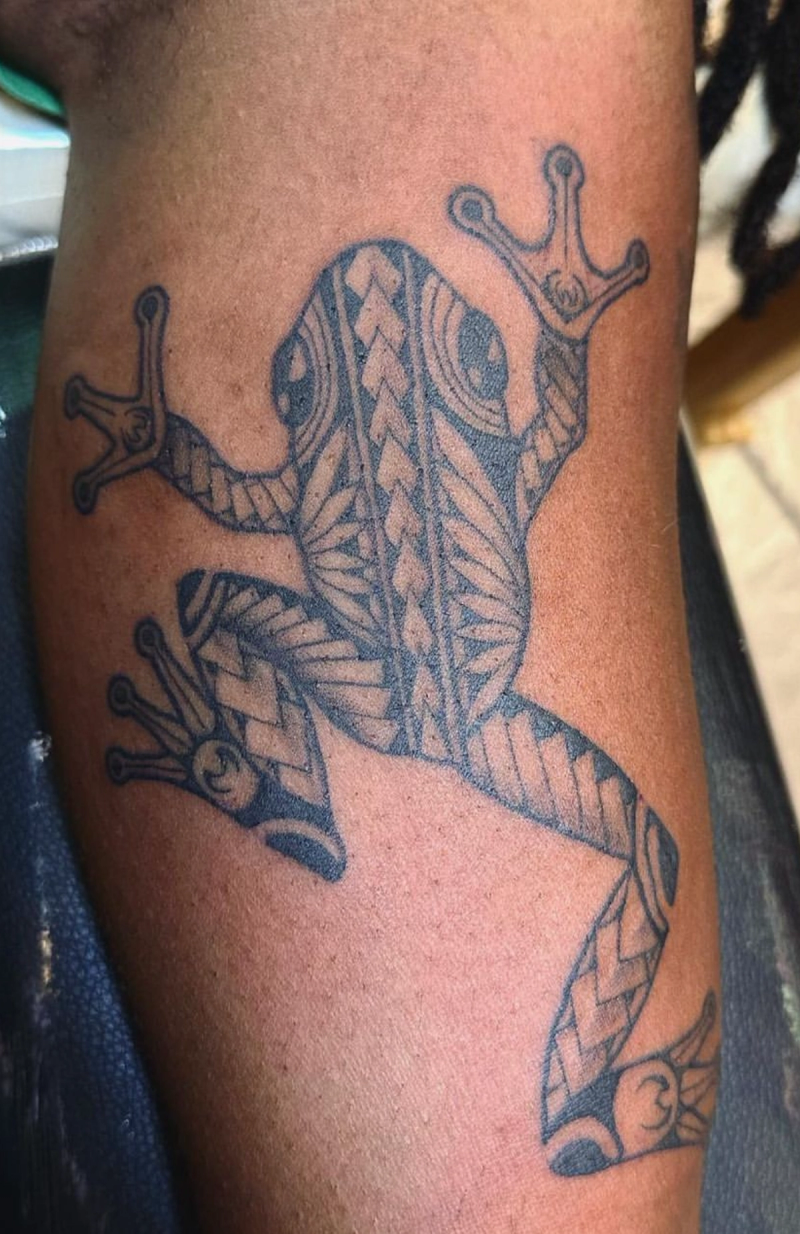 Solid black tribal frog tattoo on upper arm
