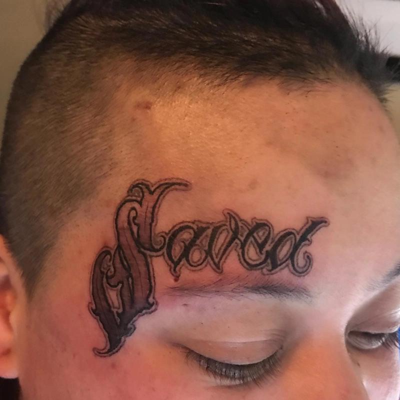 black script tattoo on face