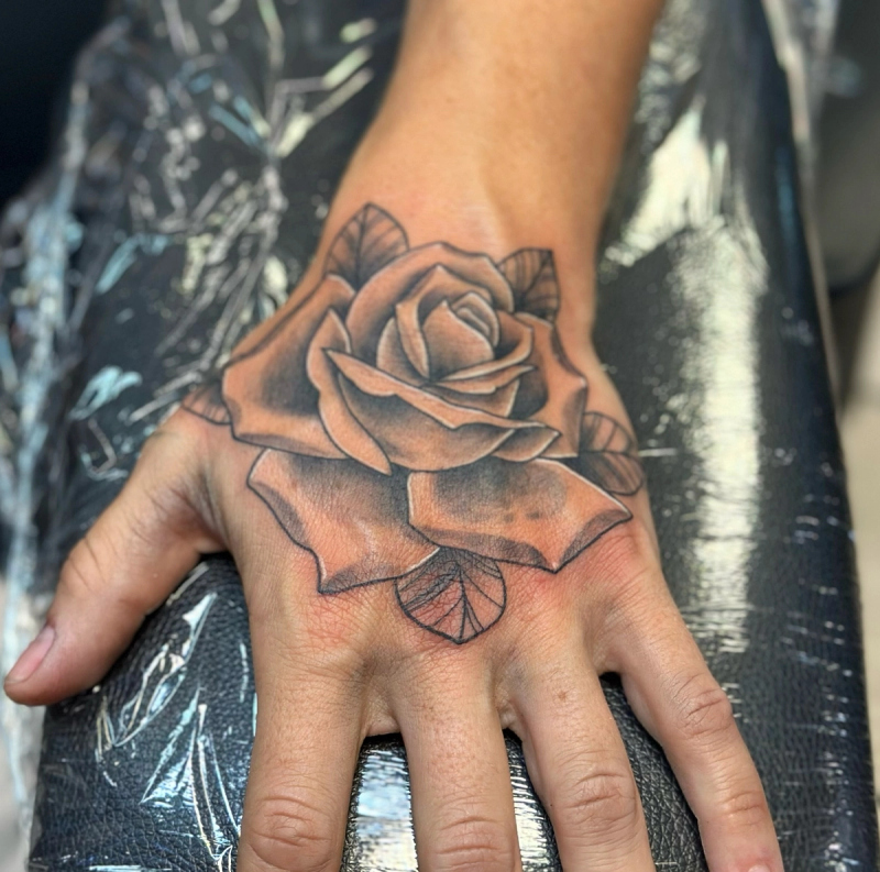 Black and grey rose tattoo on hand