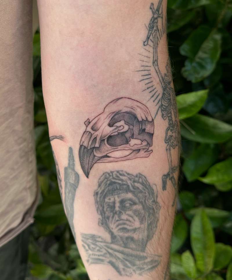 Black and grey blackwork skull and face tattoo on forearm