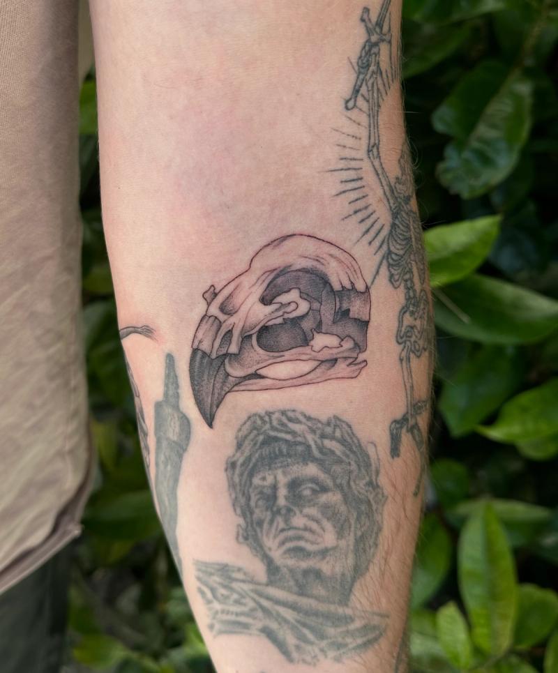 Black and grey blackwork skull and face tattoo on forearm