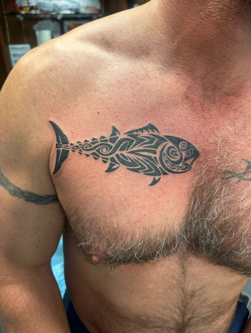 Black tribal fish tattoo on chest