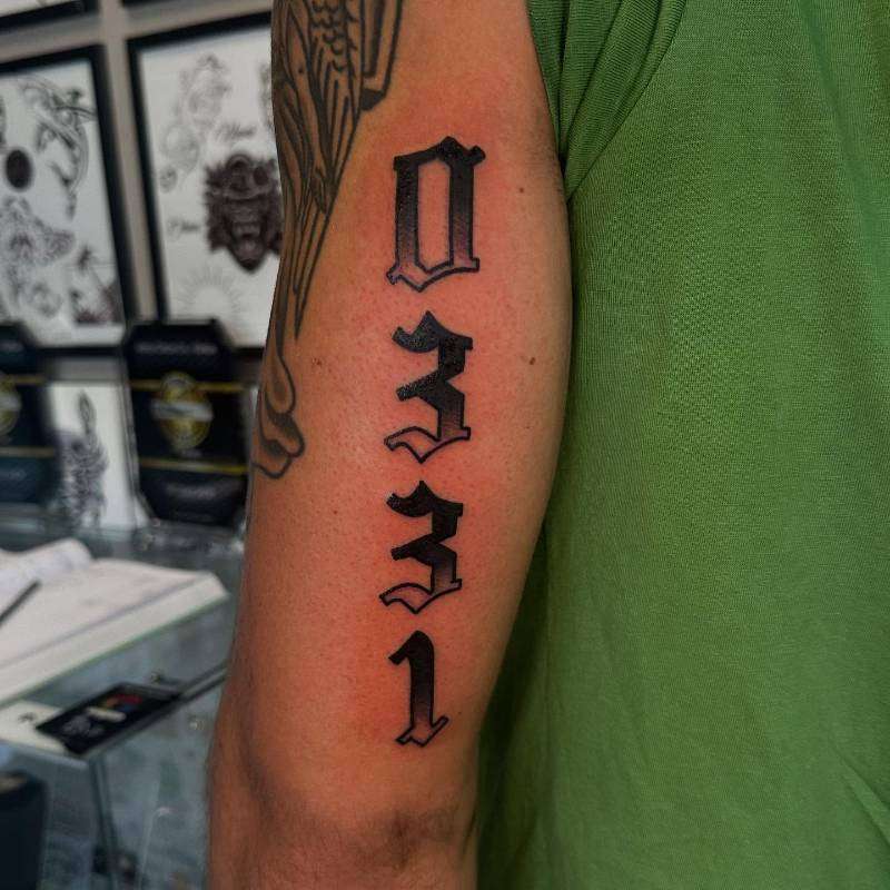 black and grey number tattoo on upper arm
