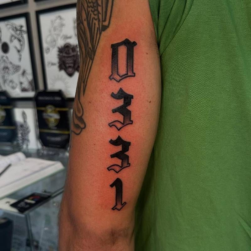 black and grey number tattoo on upper arm