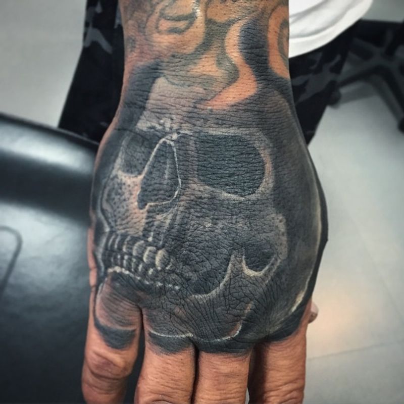 Black and grey realistic skull tattoo on hand