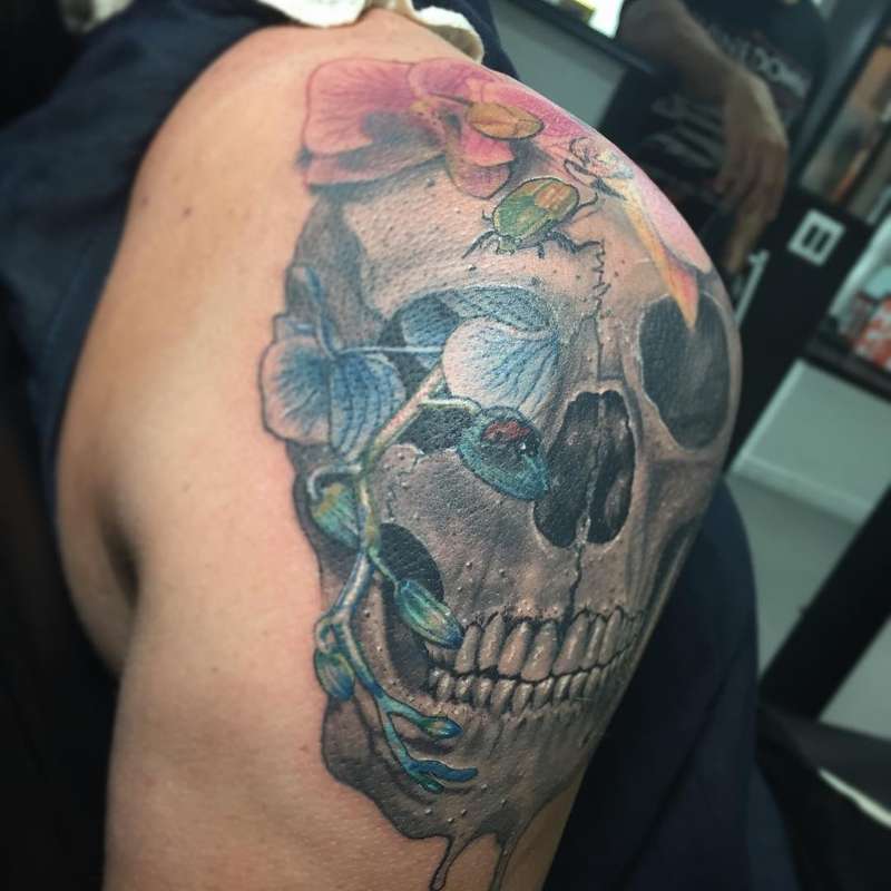 Colorful skull and floral tattoo on upper arm