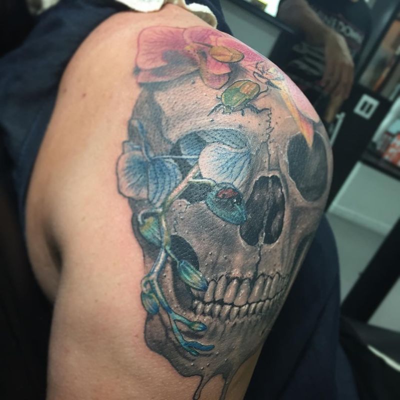 Colorful skull and floral tattoo on upper arm