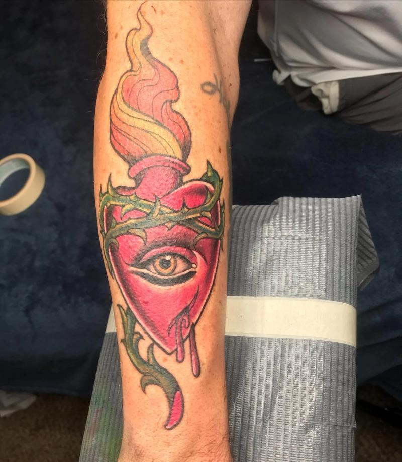 traditional tattoo of a flaming heart with an eye on forearm