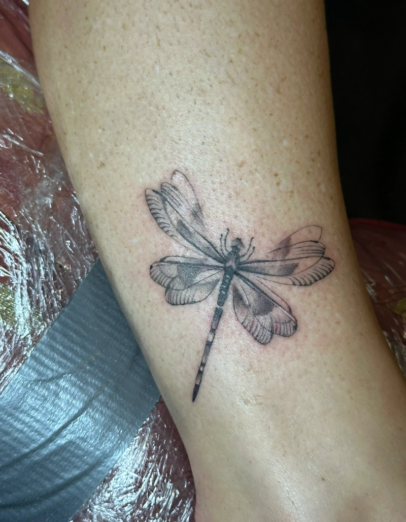 Black and grey dragonfly tattoo on calf