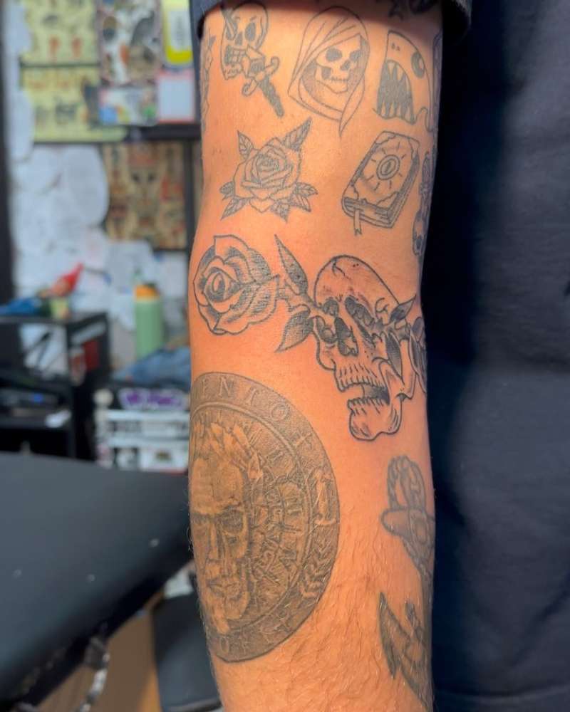 black and grey forearm tattoo with skull and rose