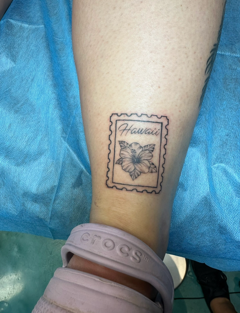 Black and grey minimalist flower stamp tattoo on calf