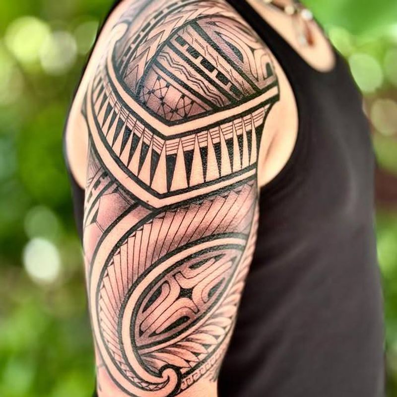 Tribal blackwork tattoo covering the upper arm