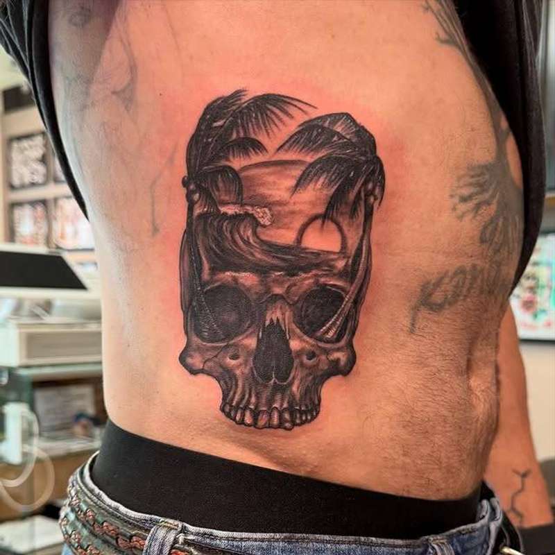 Blackwork illustrative skull with palms and sunset on torso.