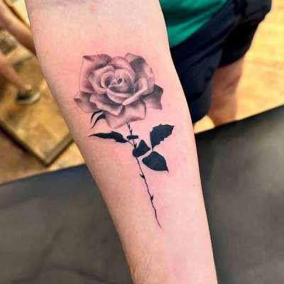 Black and grey realistic rose tattoo on forearm