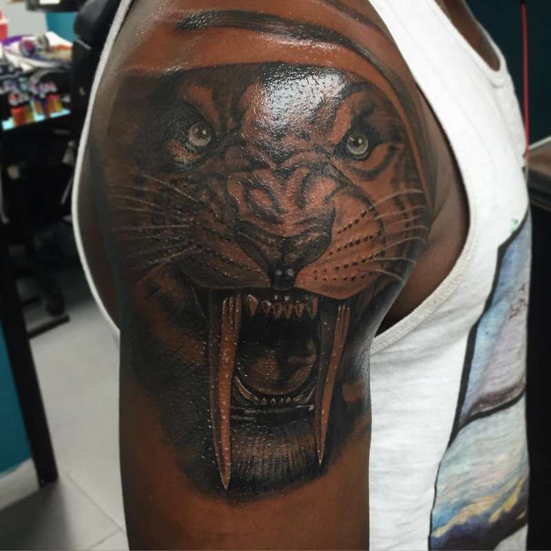 Black and grey realistic tiger face tattoo on upper arm