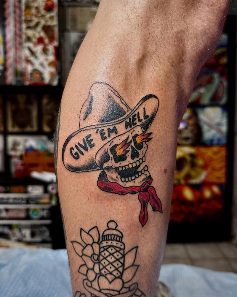 colorful cowboy skull tattoo with text on a calf