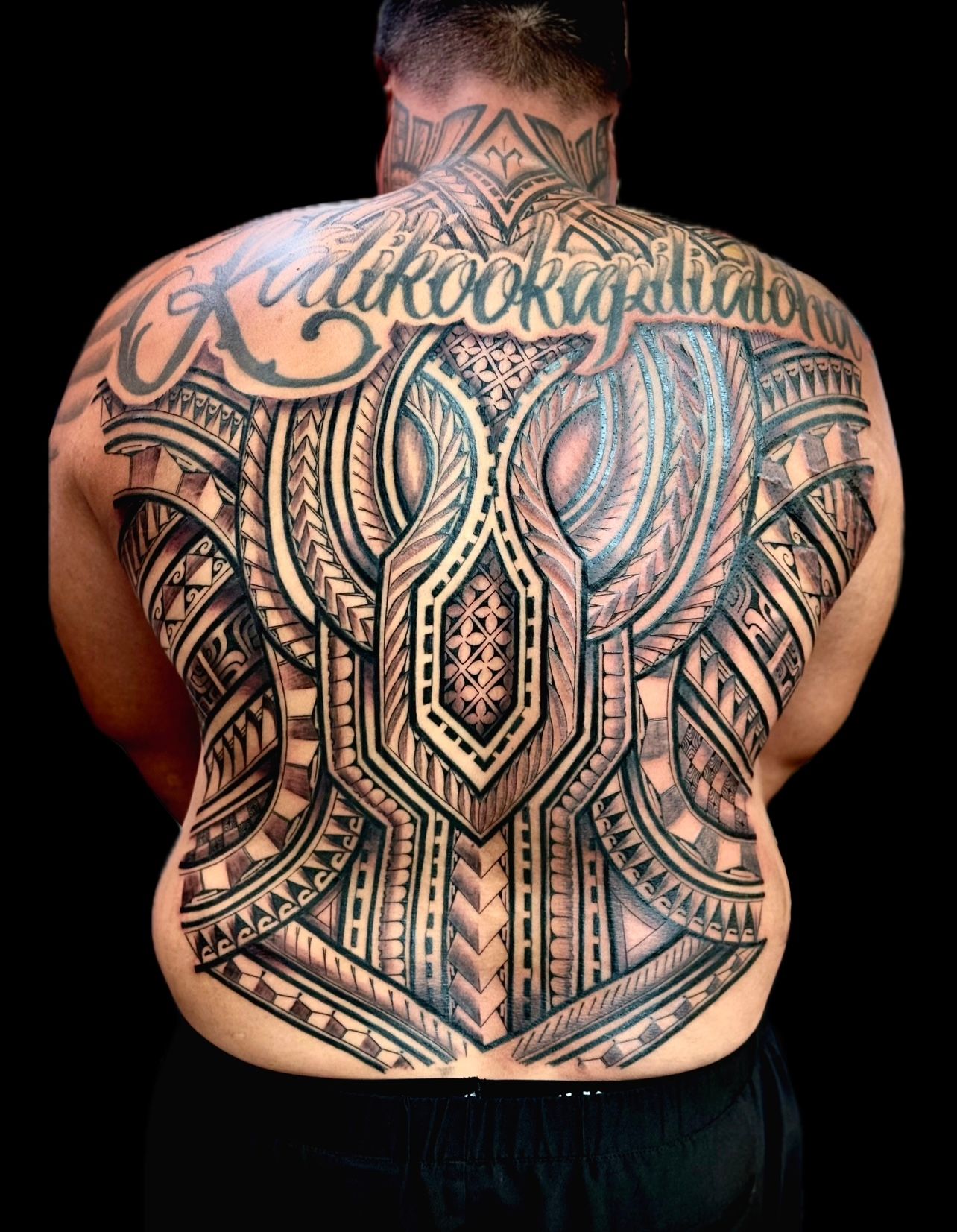 Blackwork tribal tattoo with script covering full back