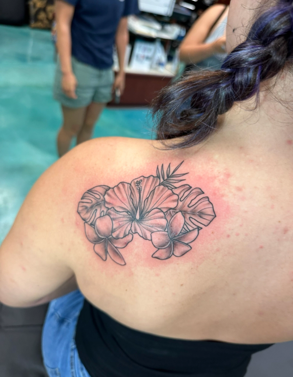 Black and grey floral tattoo on upper back.