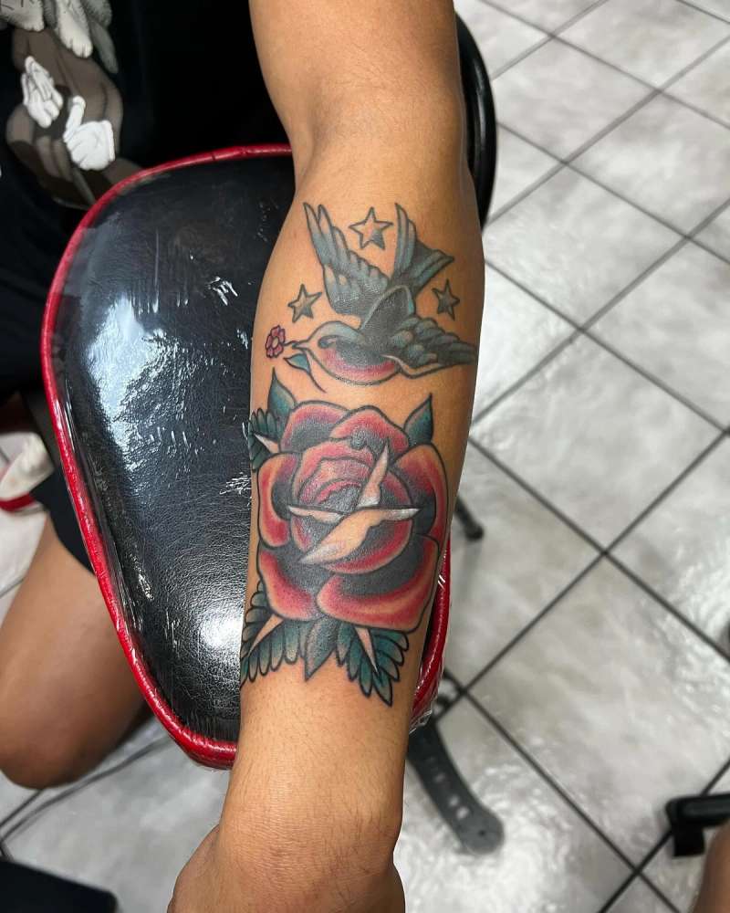 Colorful American traditional rose and bird tattoo on forearm