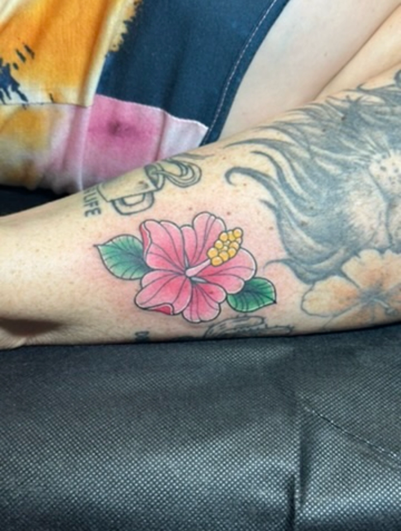 Colorful hibiscus flower tattoo on forearm