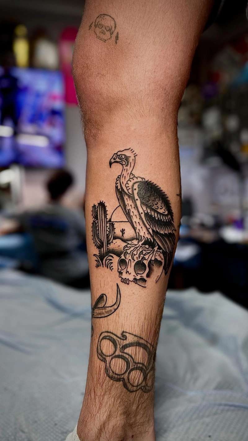 blackwork vulture and skull tattoo on calf