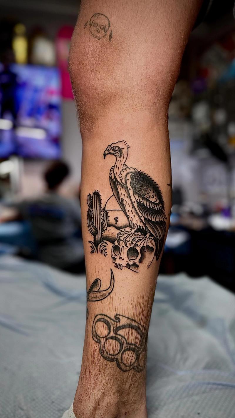 blackwork vulture and skull tattoo on calf