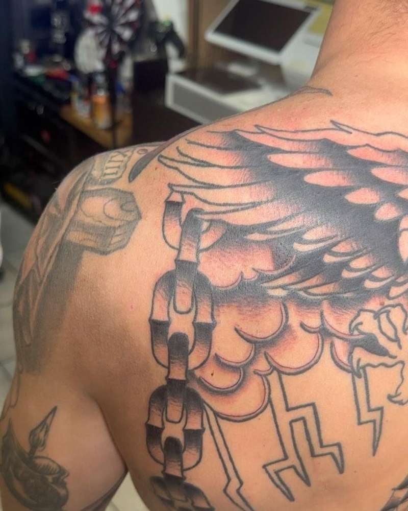 Black and grey traditional wing and chain tattoo on upper back