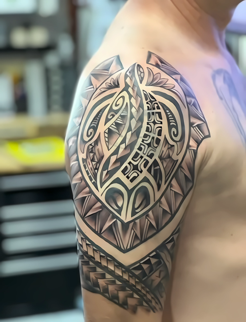 Black and grey tribal tattoo on upper arm and shoulder