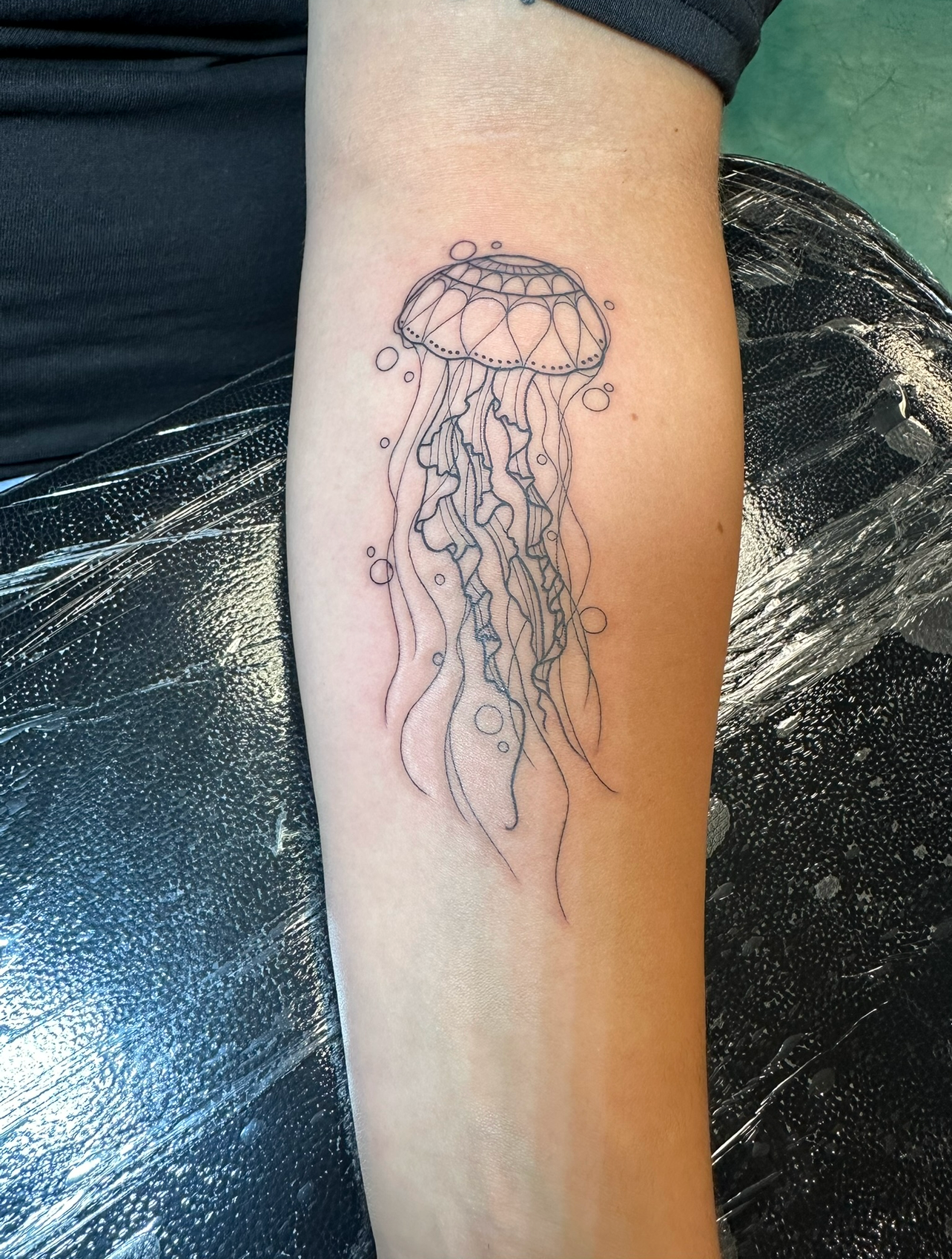 Black and grey fine line illustrative jellyfish tattoo on forearm