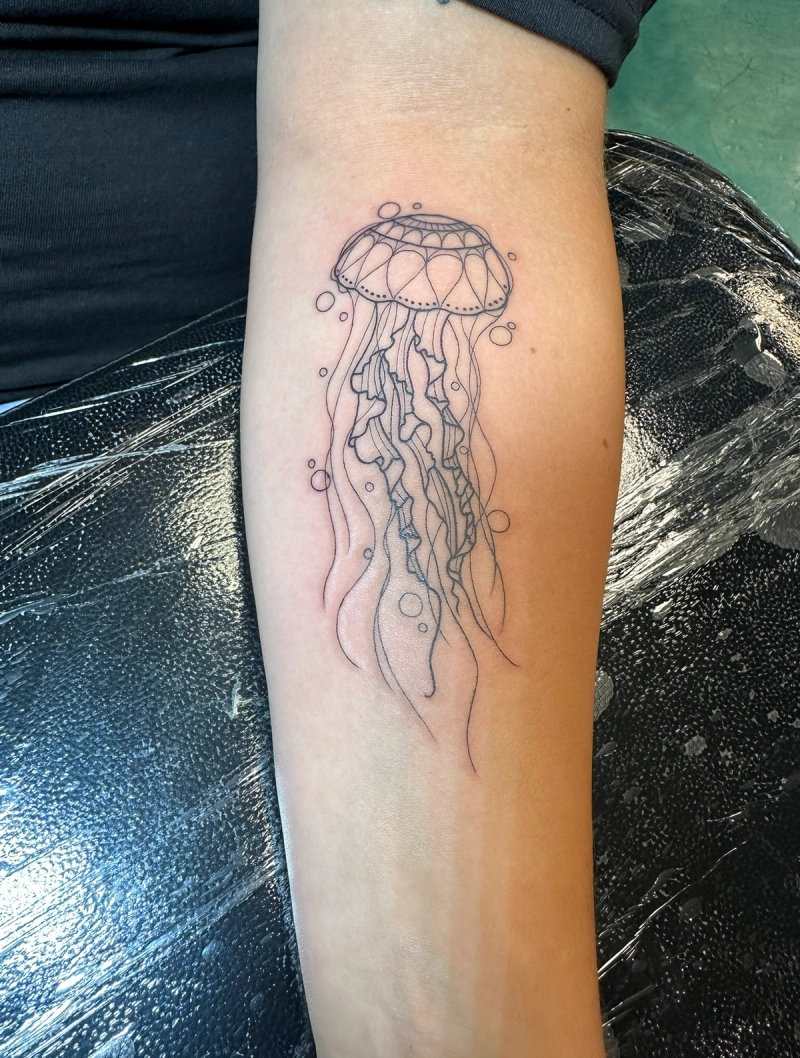 Black and grey fine line illustrative jellyfish tattoo on forearm