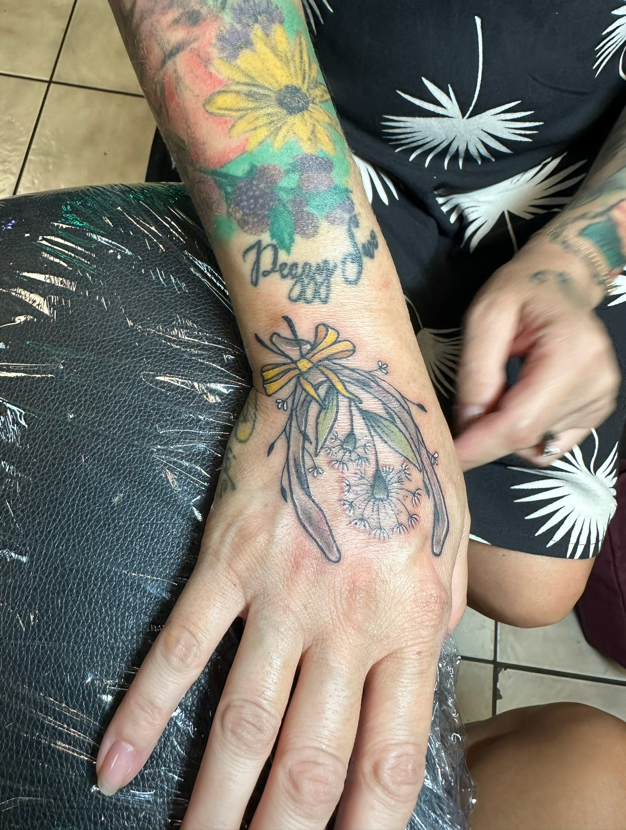 Colorful botanical watercolor tattoo on back of hand