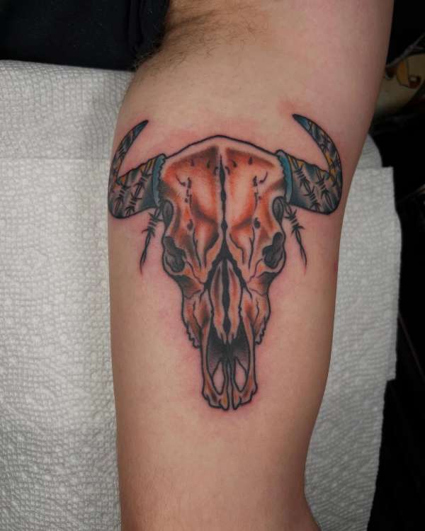 Colorful bull skull tattoo on upper arm.