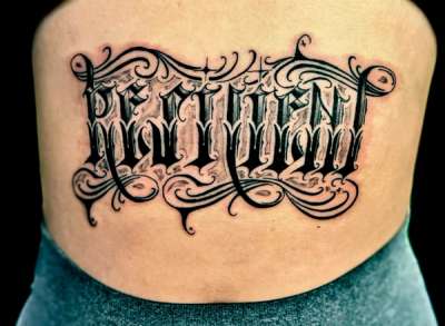 Black and grey gothic script tattoo on lower back