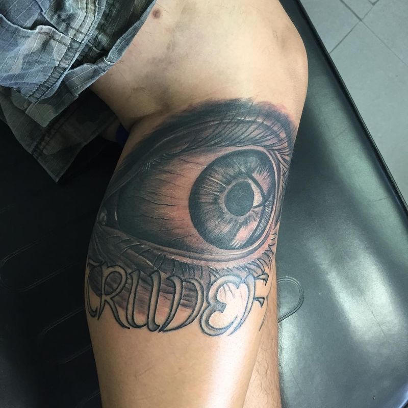 Black and grey realistic eye with script lettering on thigh