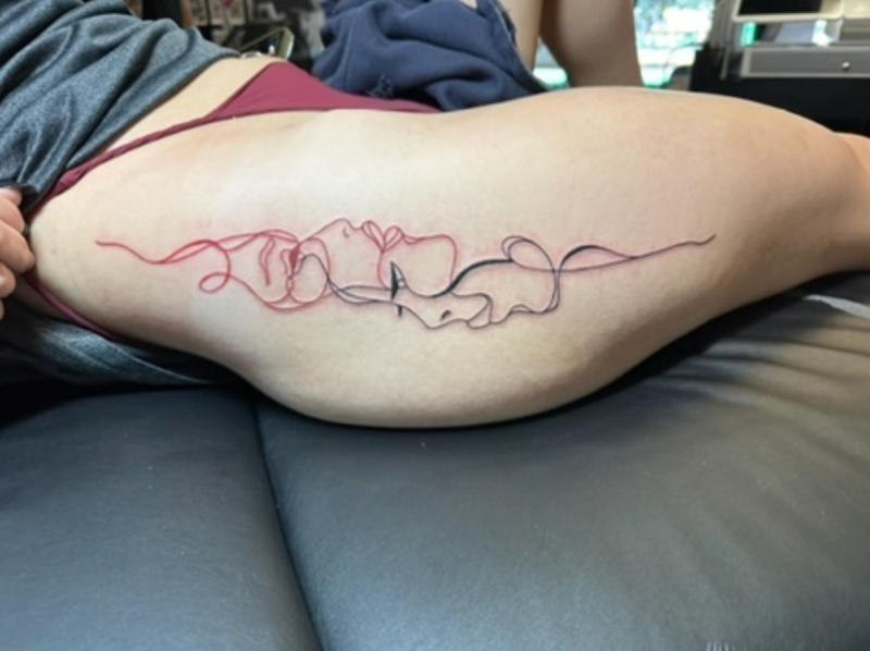 Red and black minimalist continuous line faces tattoo on thigh