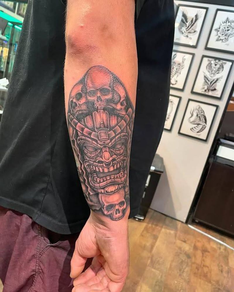 Black and grey tiki mask with skulls on forearm