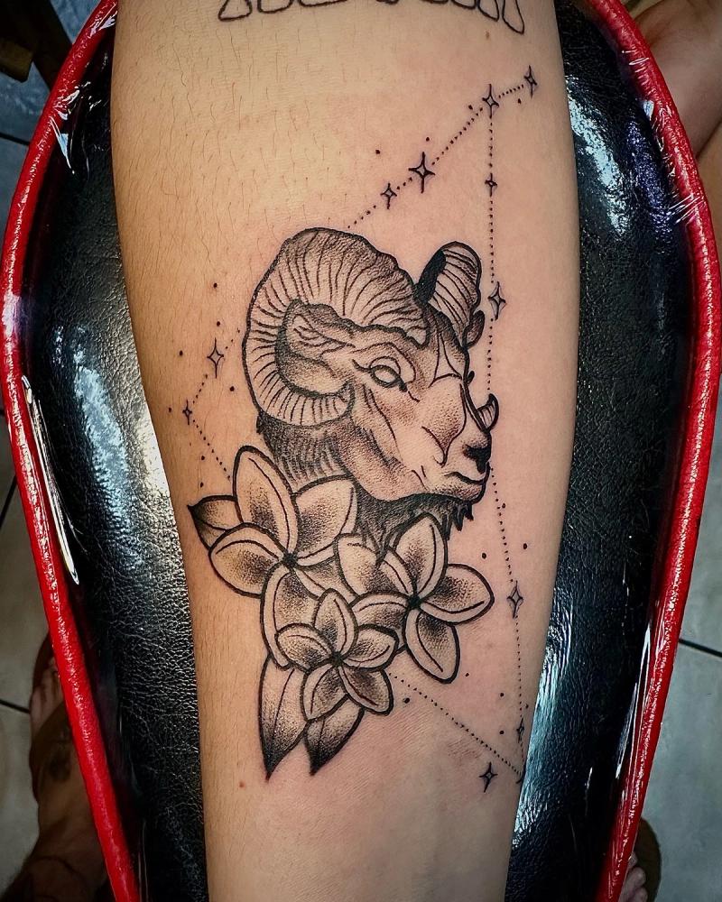 black and grey tattoo of a ram and flowers on upper arm