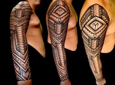 Blackwork tribal tattoo covering entire arm sleeve.