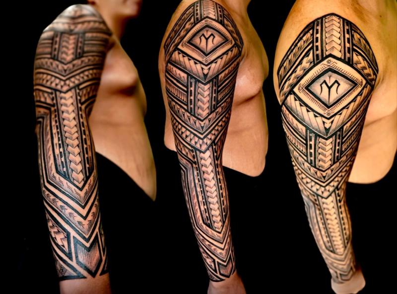 Blackwork tribal tattoo covering entire arm sleeve.