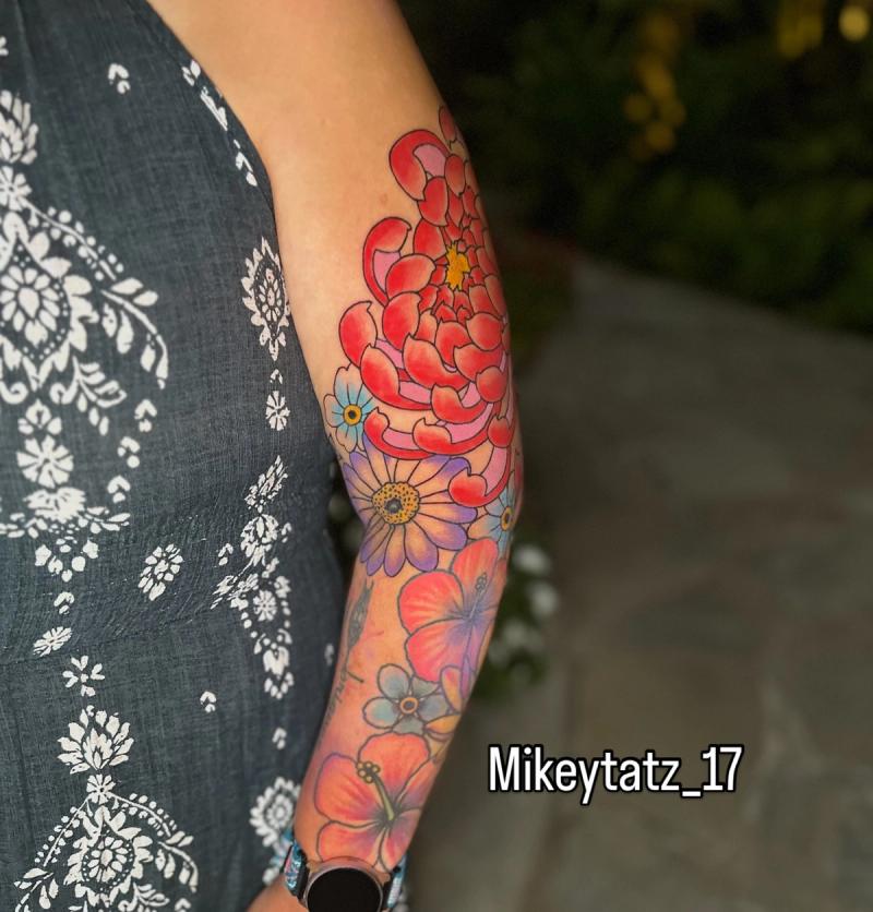 colorful forearm tattoo featuring peony daisy and hibiscus flowers