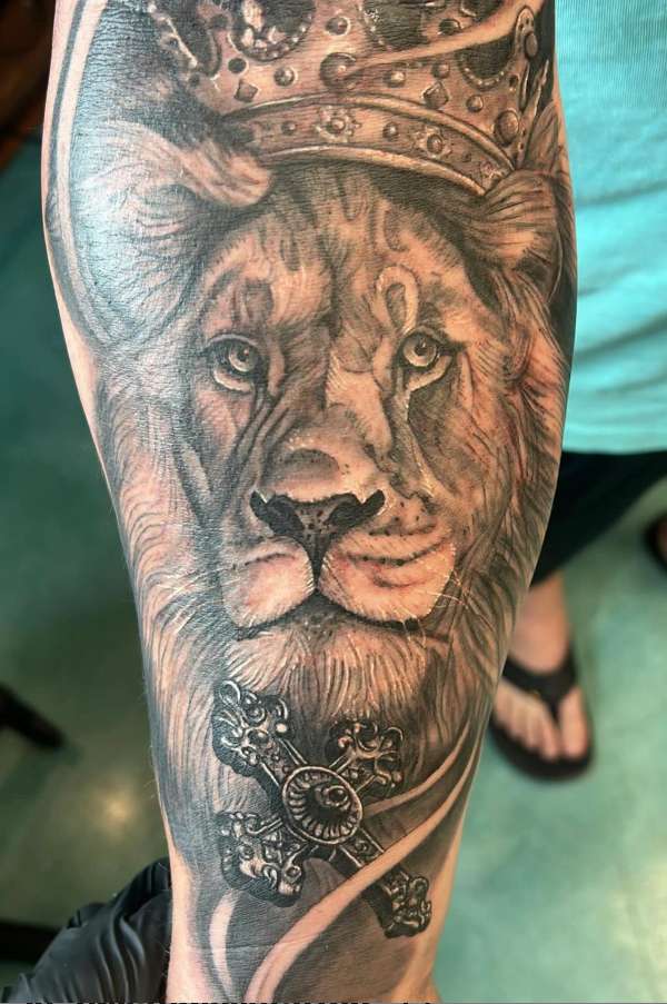 Black and grey realistic lion with crown tattoo on forearm