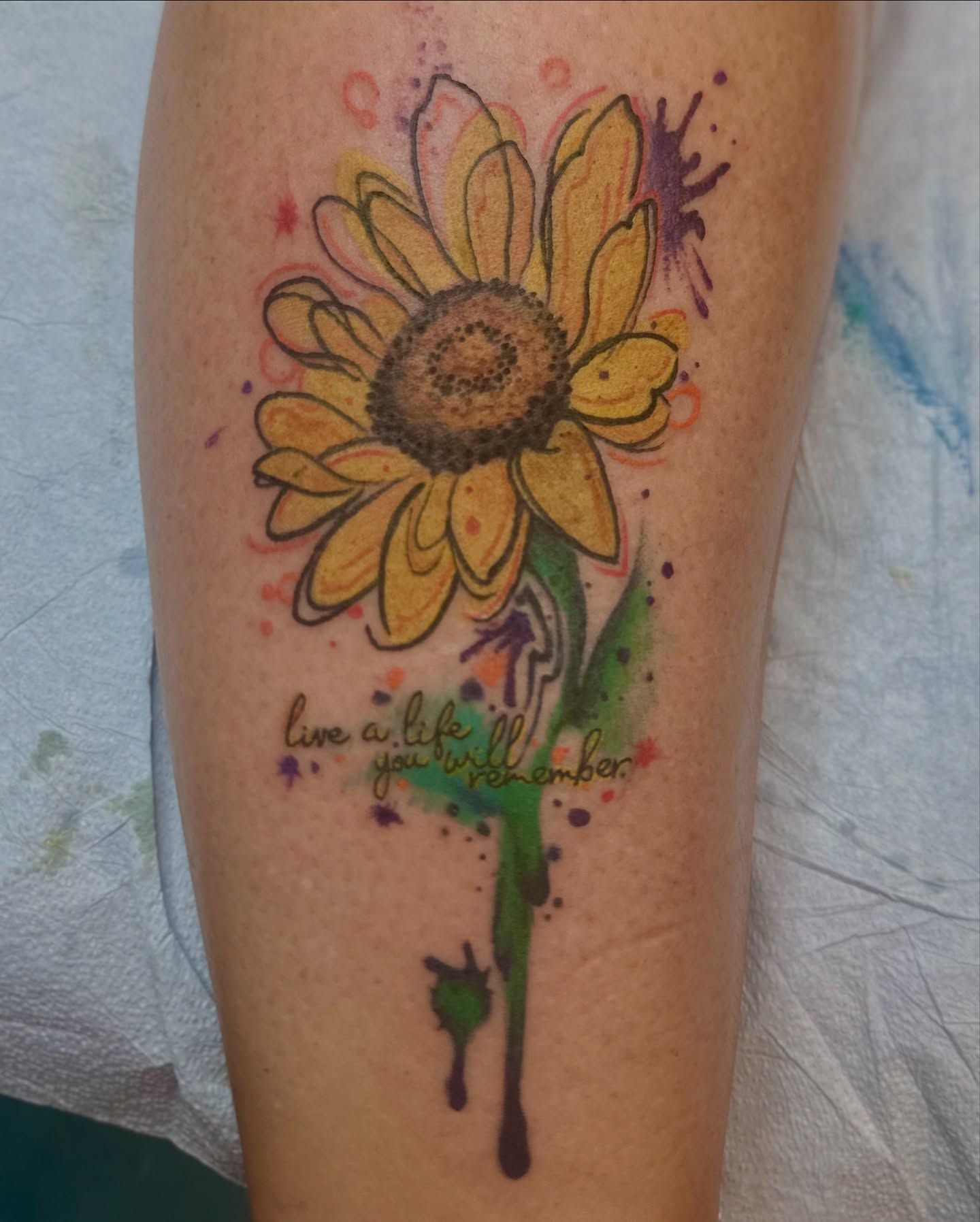 Colorful watercolor sunflower tattoo on the forearm