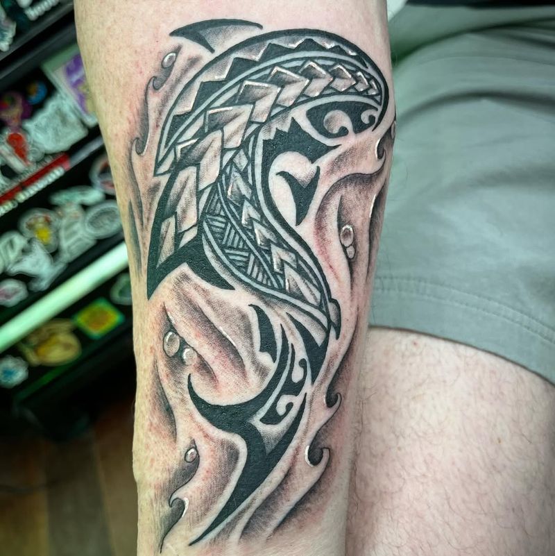 black and grey hammerhead shark tribal tattoo on forearm with water droplets