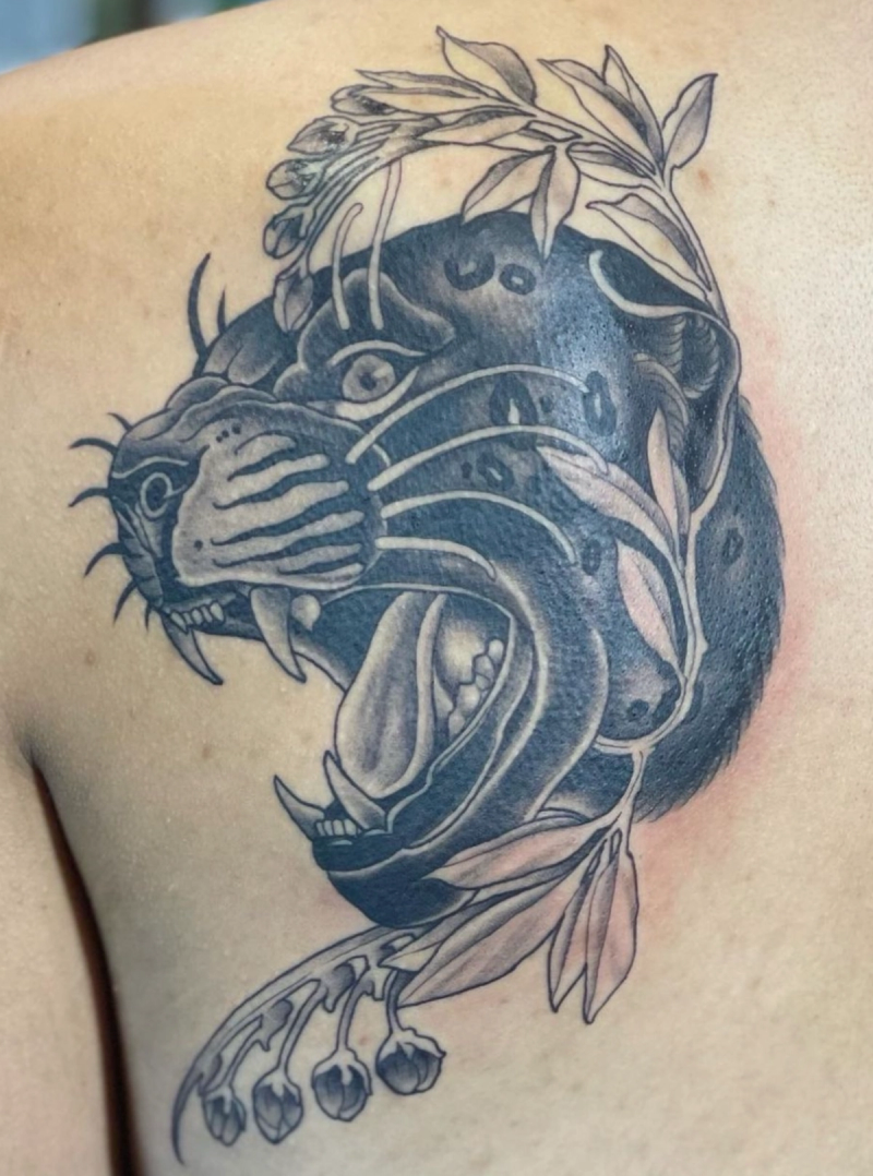 Black and grey illustrative panther and floral tattoo on upper back