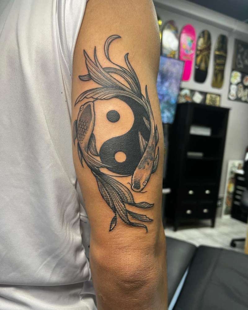 Blackwork illustrative yin-yang koi fish tattoo on upper arm