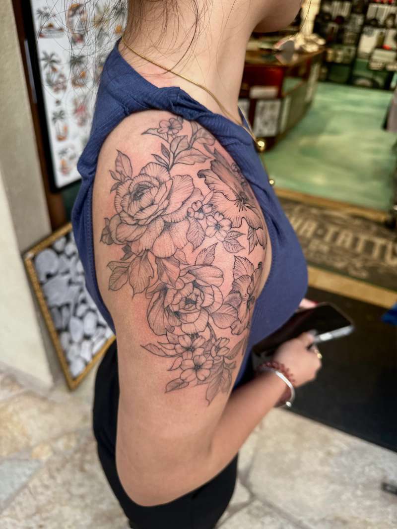 Black and grey botanical floral tattoo on upper arm