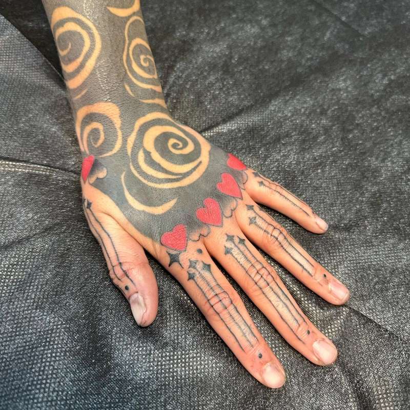 hand tattoo with spirals and hearts in black and red