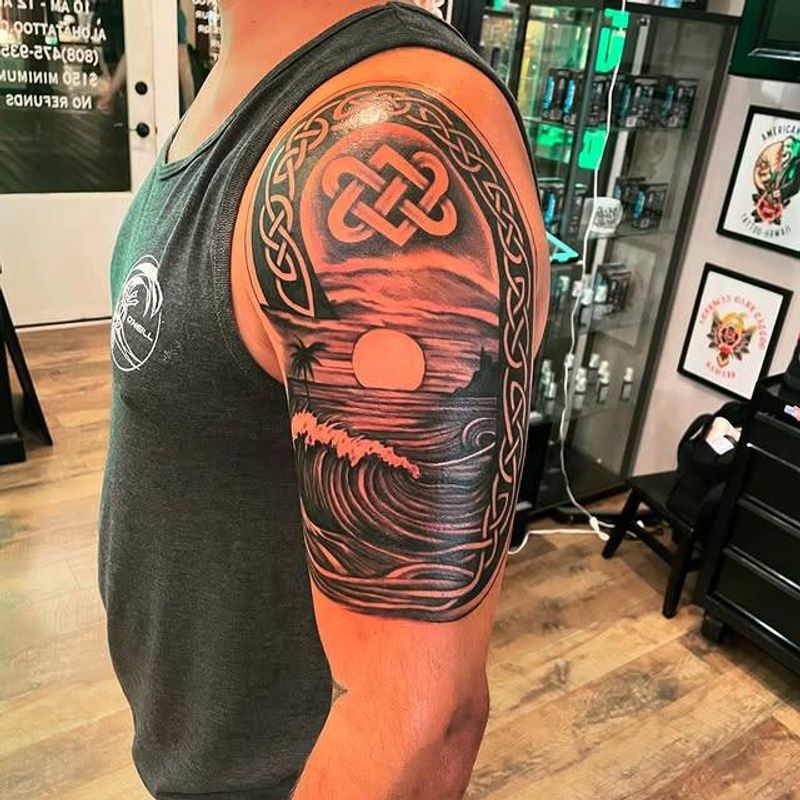 Blackwork Celtic knot and wave tattoo on upper arm