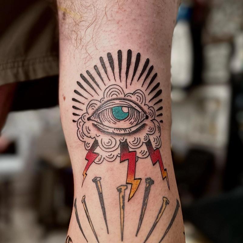 traditional tattoo of an eye with lightning bolts on a leg