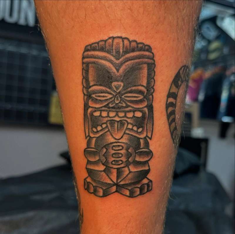 tribal blackwork tiki mask tattoo on calf